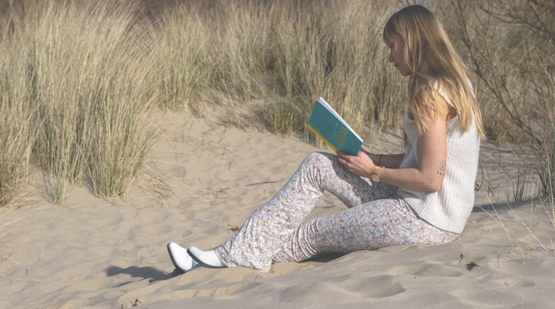 Manon een boek aan het lezen in de duinen